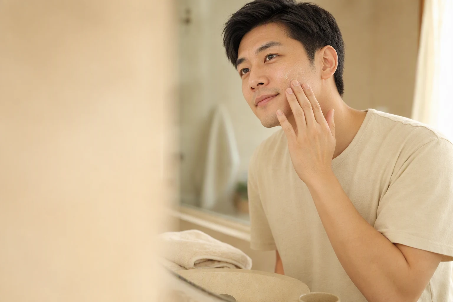 A man gently applying clear Oxora Skin Base Fluid to his cheek in soft morning light